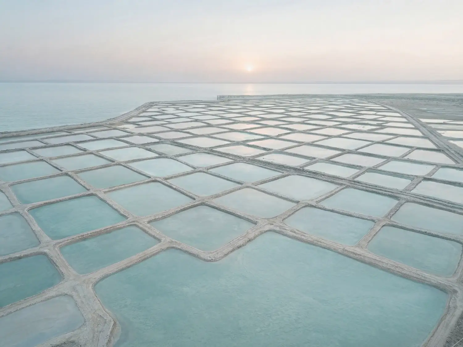 Aerial view of a large grid of shallow rectangular water basins separated by narrow embankments