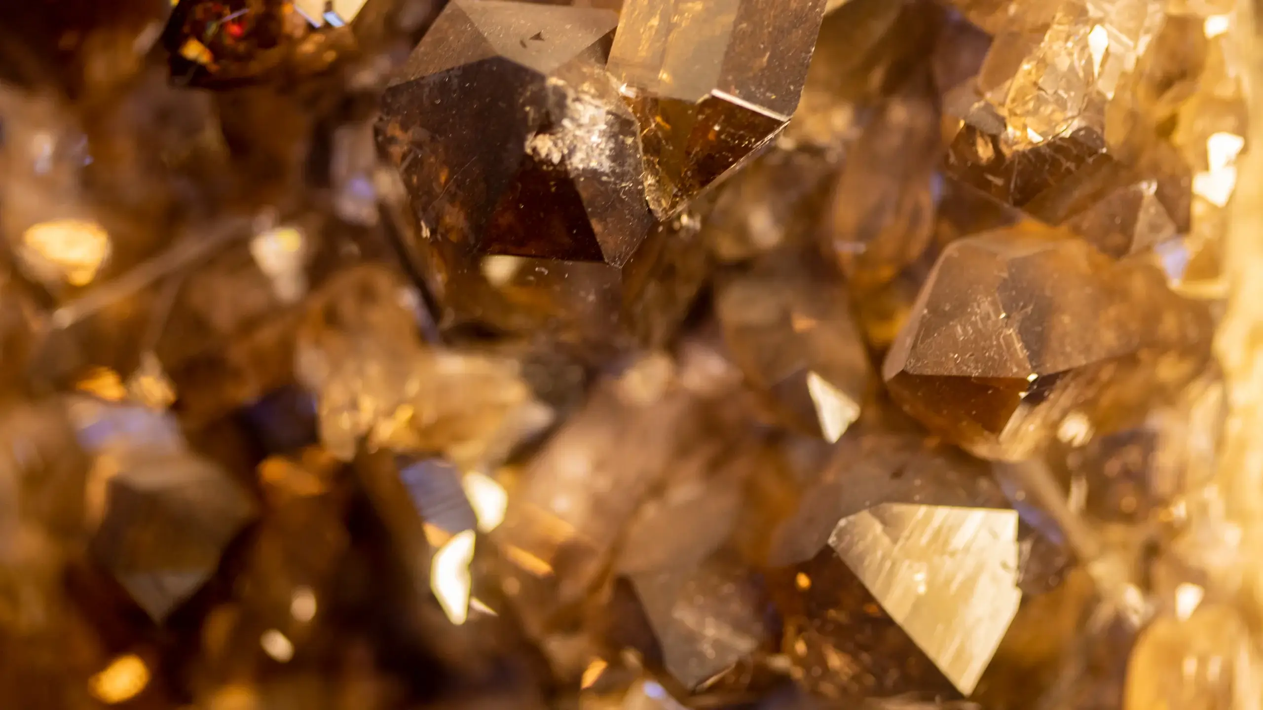 Macro close-up of amber-coloured crystal formations with sharp, faceted surfaces reflecting warm light and subtle variations in tone and texture. The image is used on the Protirus website to reflect the depth, precision, and clarity brought by enterprise cybersecurity experts working in complex and high-stakes environments