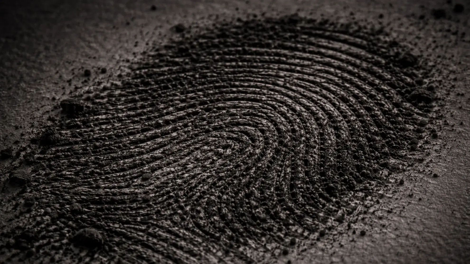 Close-up, high-contrast image of a dark fingerprint pressed into fine granular dust, showing detailed ridge patterns and texture. Representing Enterprise Cybersecurity experts