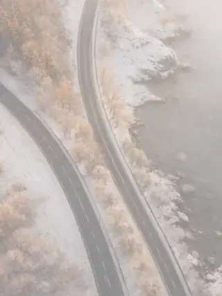 Aerial view of a winding road beside water in winter, conveying guided direction in enterprise cybersecurity consultancy.